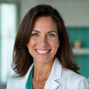 Professional headshot of Dr. Alana Reed, a warm and intelligent female doctor in her 40s, with a gentle smile, against a soft, light background. She has kind eyes.